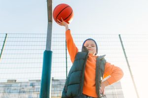 decak drzi kosarkasku loptu u visoko podignutoj ruci